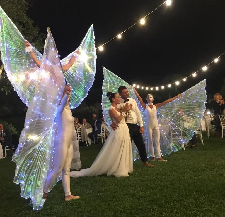 Street artist with luminous wings at a wedding